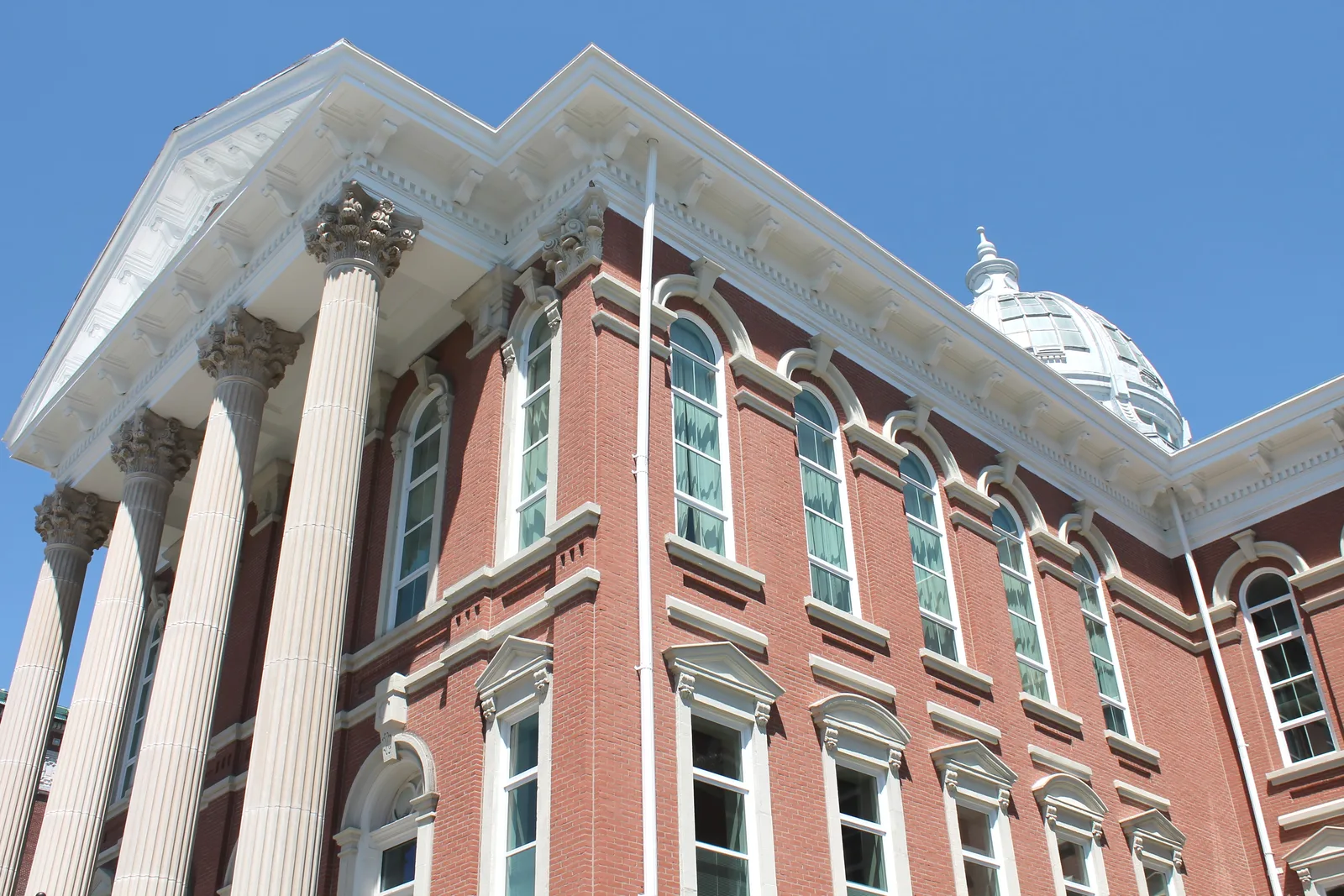 Red brick building featuring white stone columns and a domed roof.
