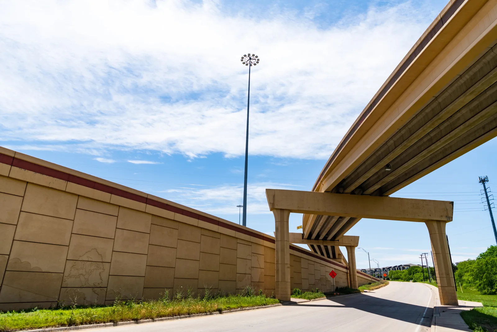 Concrete highway overpass and retaining wall above a local road.
