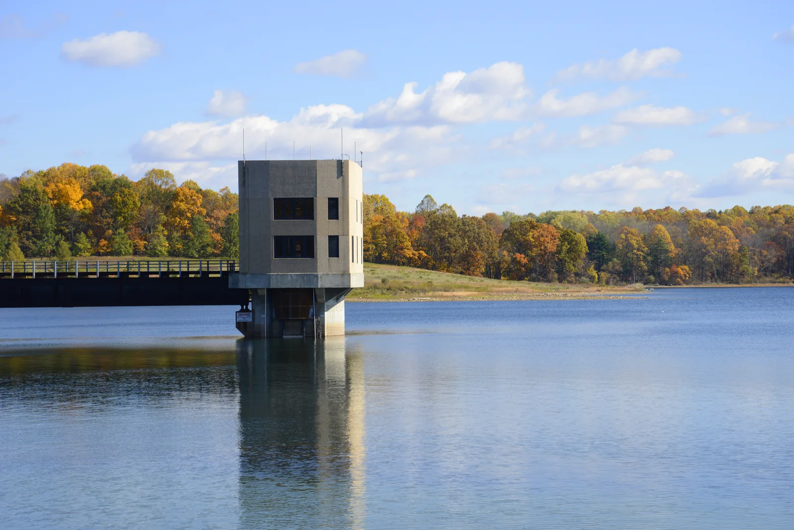 Concrete water intake structure in a reservoir bordered by trees.