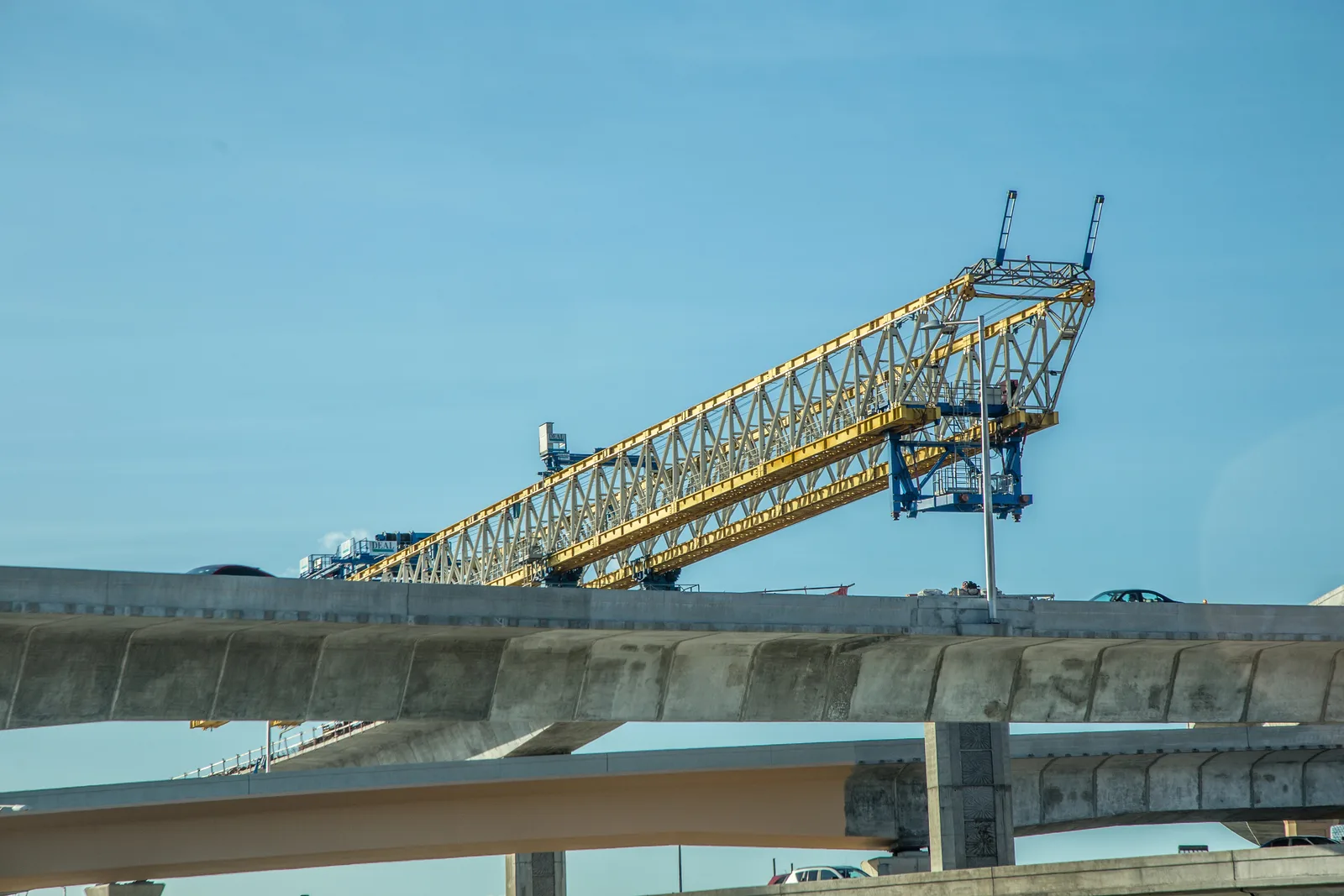 Yellow gantry crane constructing an elevated highway bridge.