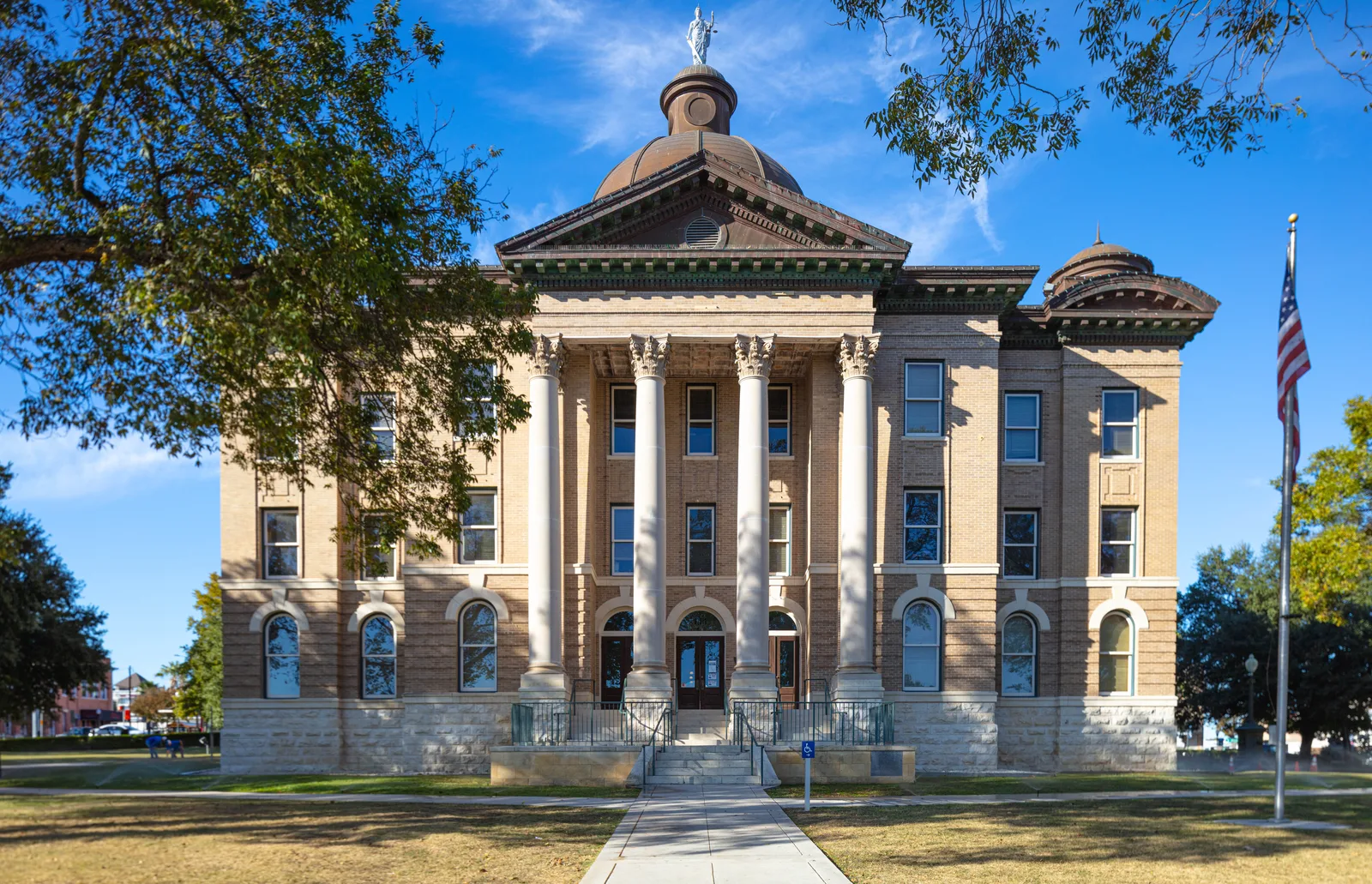 A historic municipal building featuring classical columns and a central dome against a clear blue sky.