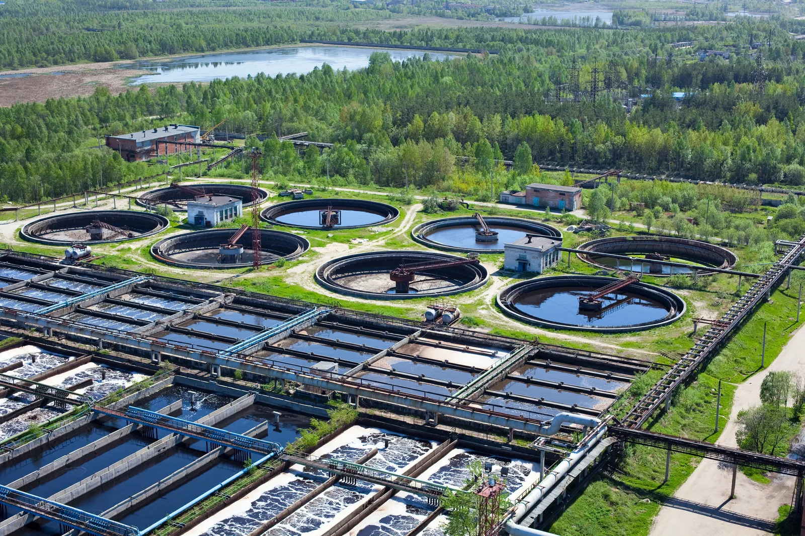 Aerial view of a wastewater treatment plant featuring circular clarifiers and rectangular aeration basins.