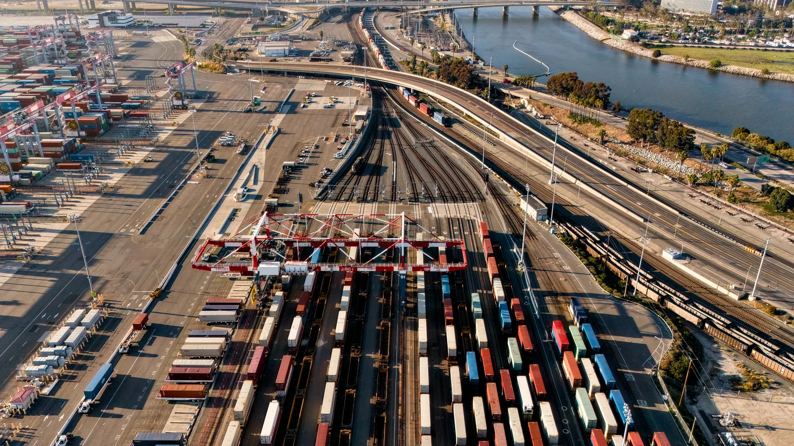 Aerial view of an intermodal port terminal with freight trains and shipping containers.
