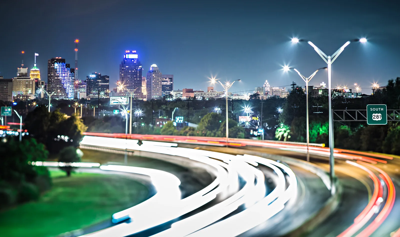 Long-exposure night traffic on Highway 281 heading toward the San Antonio skyline.