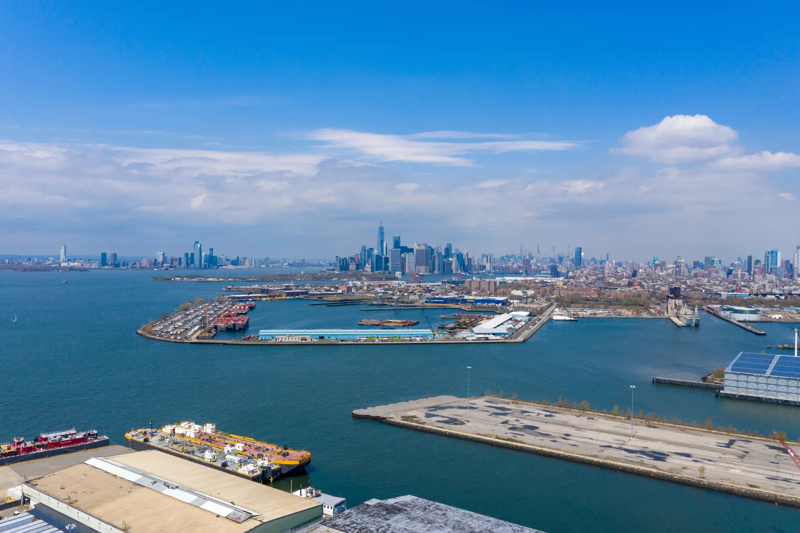 Aerial view of a commercial harbor port and distant city skyline.